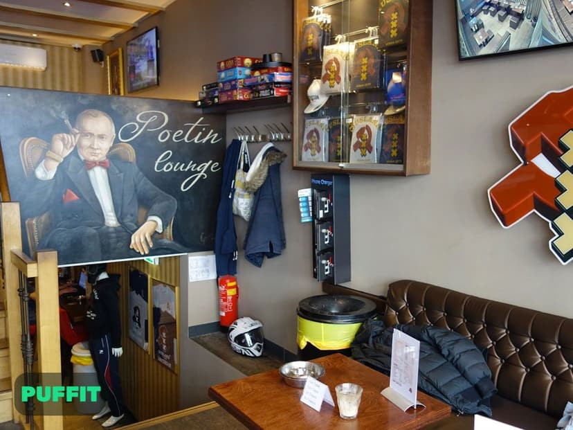 ציור Poetin Lounge וספת עור חומה בטרקלין של רוסלנד, לצד ויטרינת מזכרות ועמדת טעינה לטלפונים